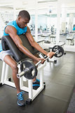 Determined young man lifting barbell in gym