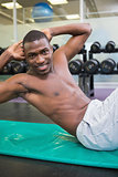 Portrait of shirtless man doing abdominal crunches in gym