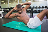 Shirtless man doing abdominal crunches in gym
