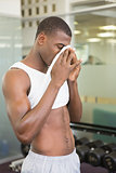 Fit man wiping sweat after workout in gym
