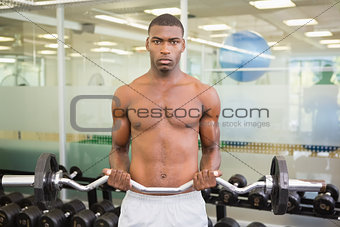 Portrait of serious man lifting barbell in gym