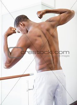 Rear view of shirtless muscular man flexing muscles
