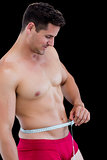 Side view of fit man measuring waist