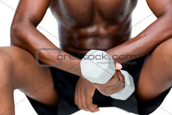 Mid section of fit shirtless man lifting dumbbell