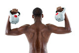 Rear view of shirtless fit man lifting kettle bells