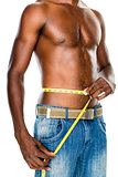 Mid section of a fit shirtless man measuring waist
