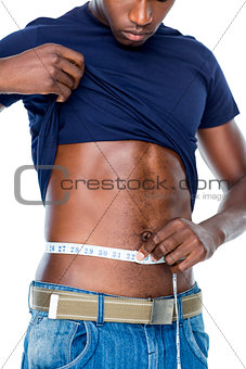 Mid section of a fit young man measuring waist