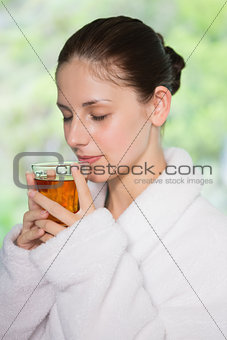 Beautiful woman in bathrobe having tea