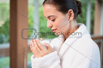 Beautiful young woman in bathrobe having tea
