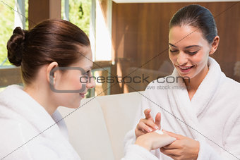 Woman applying cream to friend's hand