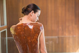 Attractive woman with chocolate back mask at spa center