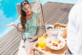 Woman looking at cropped waiter with breakfast tray