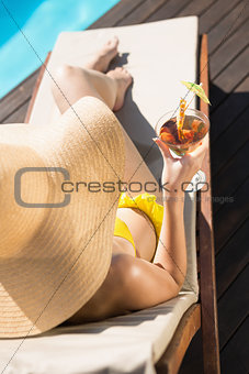Beautiful woman holding drink by swimming pool