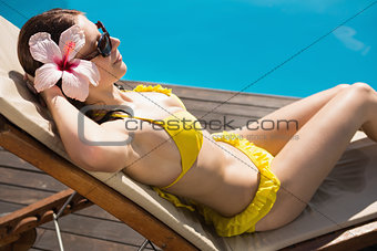 Beautiful woman in bikini relaxing by swimming pool