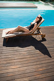 Beautiful woman in bikini relaxing by swimming pool