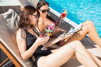 Women with drinks by swimming pool