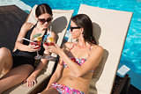 Women toasting drinks by swimming pool