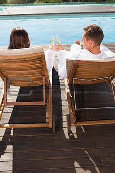 Couple toasting champagne by swimming pool