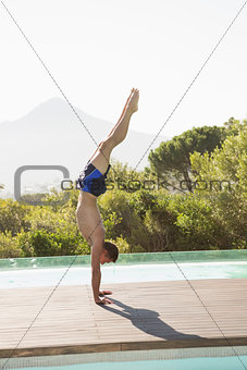 Man performing handstand by swimming pool