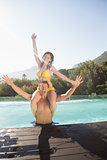 Man carrying cheerful woman by swimming pool