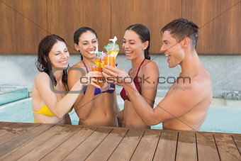 Cheerful people toasting drinks in the swimming pool