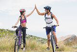 Athletic couple mountain biking while high fiving