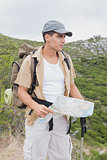 Hiking man holding map on mountain terrain