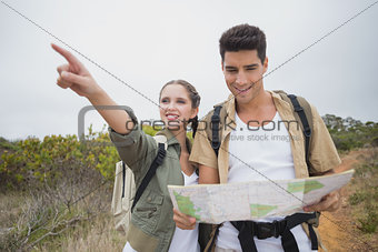 Couple with map pointing ahead on mountain terrain