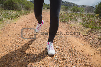 Low section of woman running on country road