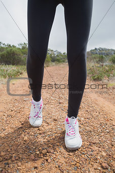Low section of woman walking on country road