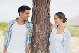 Smiling couple standing by tree trunk