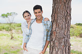 Smiling couple standing by tree trunk