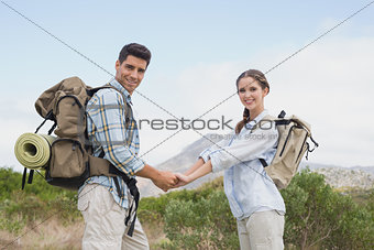 Hiking couple holding hands on mountain terrain