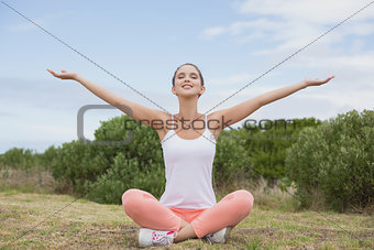 Woman sitting with arms raised on countryside landscape