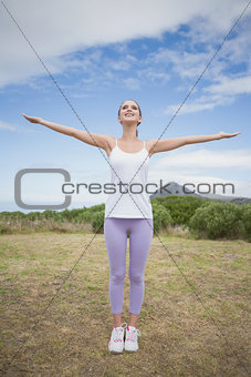 Woman standing with arms raised on countryside landscape
