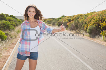 Smiling woman hitchhiking on countryside road