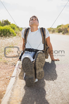 Hiking man sitting on countryside road