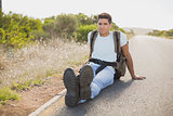 Hiking man sitting on countryside road