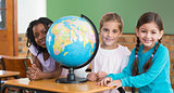 Cute pupils sitting in classroom with globe