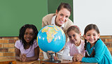Cute pupils and teacher in classroom with globe