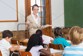Pretty teacher talking to the young pupils in classroom