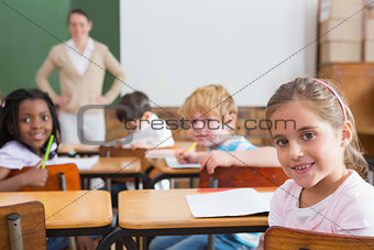 Pupils and teacher smiling at camera in classroom