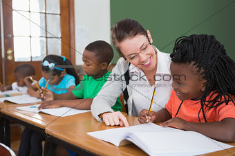 Pretty teacher helping pupil in classroom