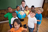 Cute pupils pointing to globe in classroom
