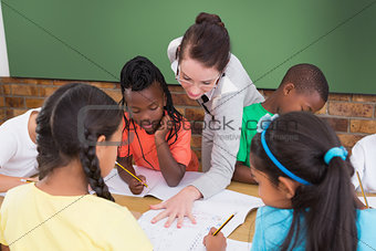 Teacher and pupils working at desk together