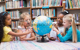 Cute pupils looking at globe in library