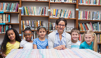Cute pupils and teacher looking at camera in library