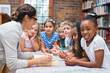 Cute pupils and teacher reading in library