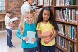 Cute pupils and teacher looking for books in library