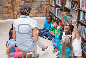 Cute pupils and teacher having class in library